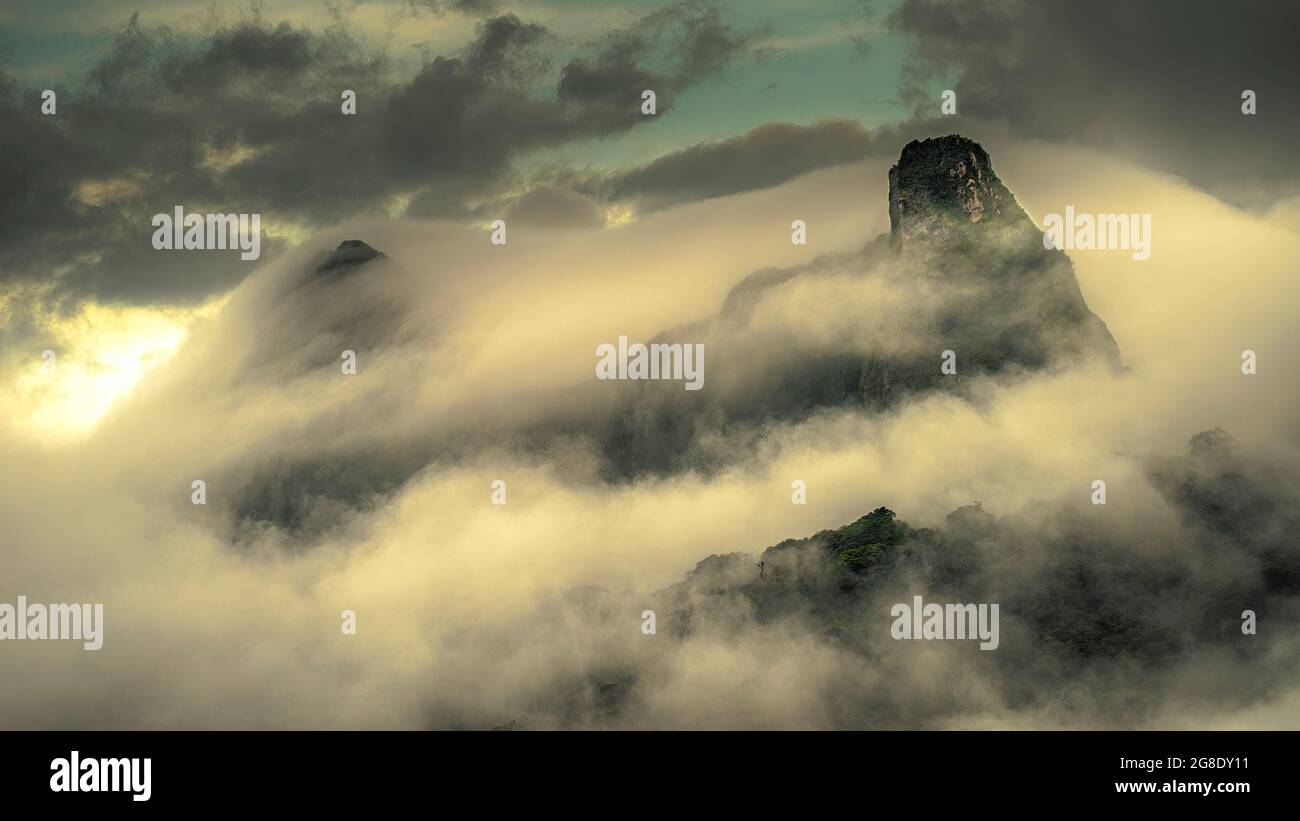 Bergwolkenwald in einer nebligen Sonnenuntergangsumgebung Stockfoto