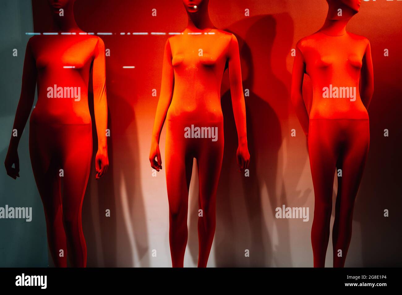 Drei Mannequins im Schaufenster unter rotem Licht Stockfoto