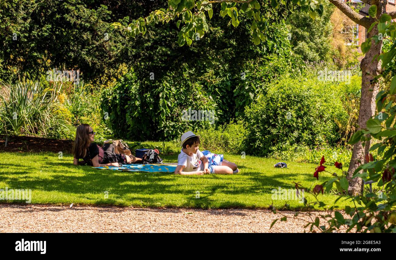 Mutter und Sohn entspannen sich auf einem Teppich auf einem Rasen im Chelsea Physic Garden in London. Stockfoto
