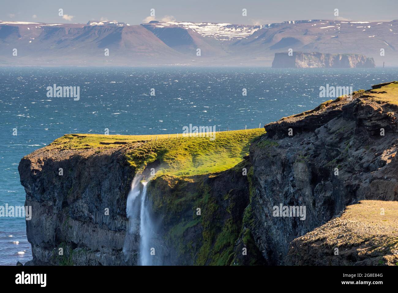 Der Wasserfall fällt über die Klippe und wird vom Wind weggeblasen, im Hintergrund Saga Island Drangey, Skagi Peninsula, Skagafjoerour, Norourland Vestra Stockfoto