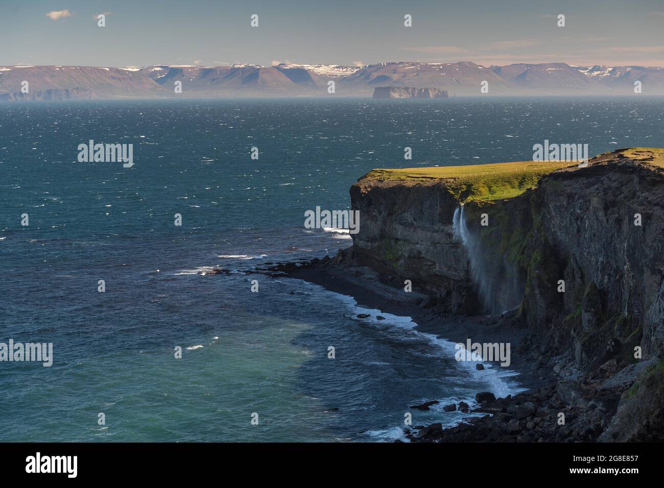 Der Wasserfall fällt über die Klippe und wird vom Wind weggeblasen, im Hintergrund Saga Island Drangey, Skagi Peninsula, Skagafjoerour, Norourland Vestra Stockfoto