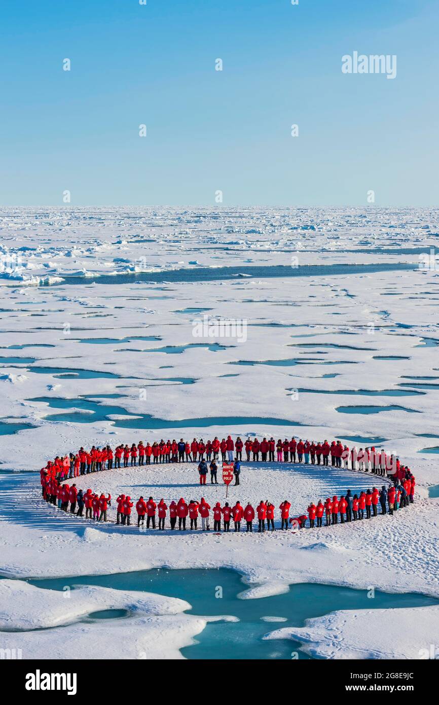 Menschen, die einen Kreis bilden, um sich zu merken, dass sie am Nordpol, der Arktis, angekommen sind Stockfoto