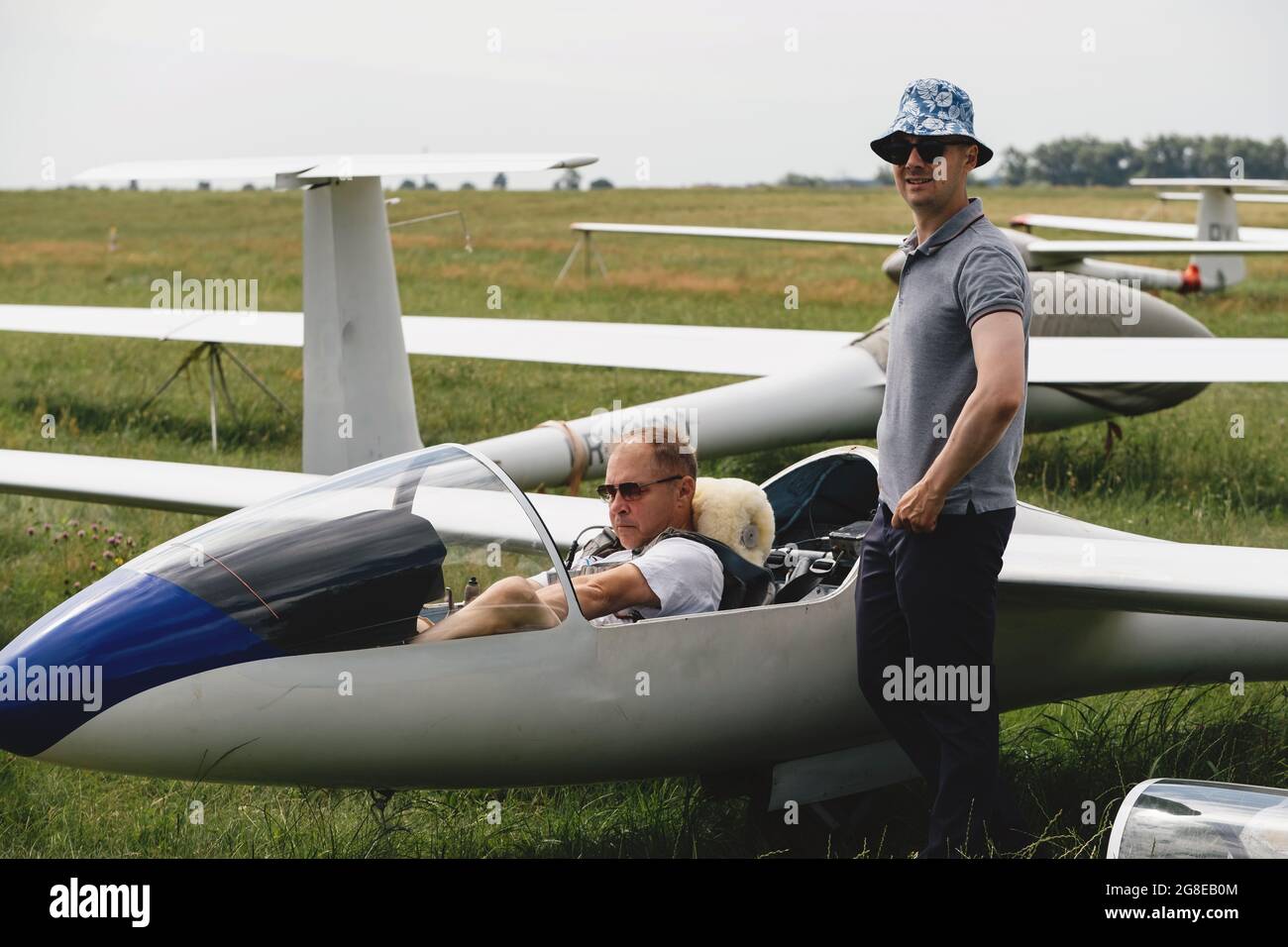 Segelclub, der sich auf den Flug mit dem Segelflugzeug vorbereitet. Kleiner Flugsport. Zwei Mann überprüfen Kabine Instrumentenfeld von Vintage-Flugzeug Stockfoto