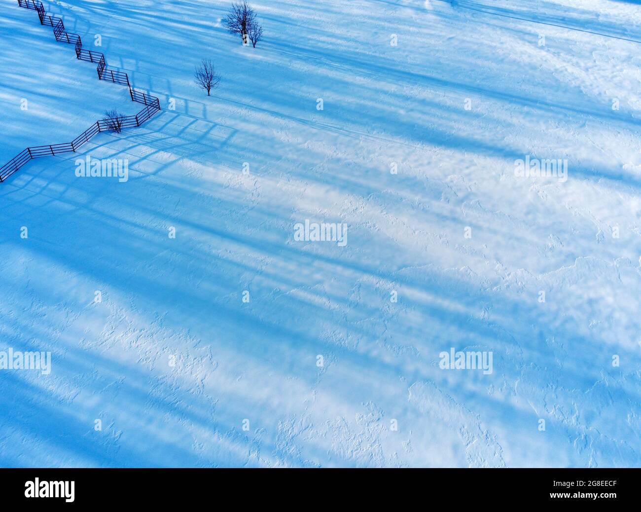 Blaue Schatten fallen über gefrorenen Schnee, um ein Interessantes Muster zu erzeugen Stockfoto