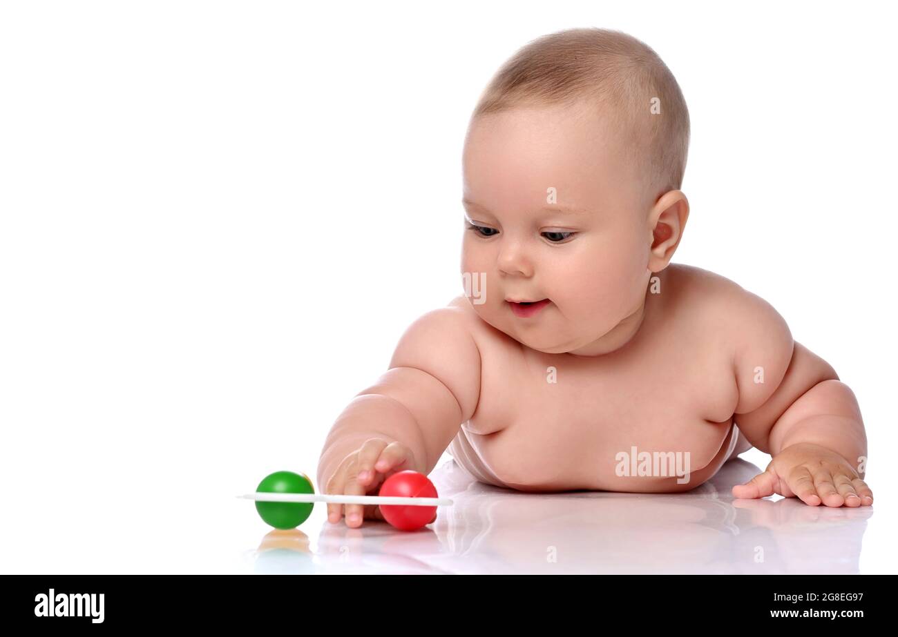 Lächelndes Kleinkind Baby Mädchen Kind in Windel liegt auf ihrem Bauch spielen mit Rassel, berühren mit der Hand Stockfoto