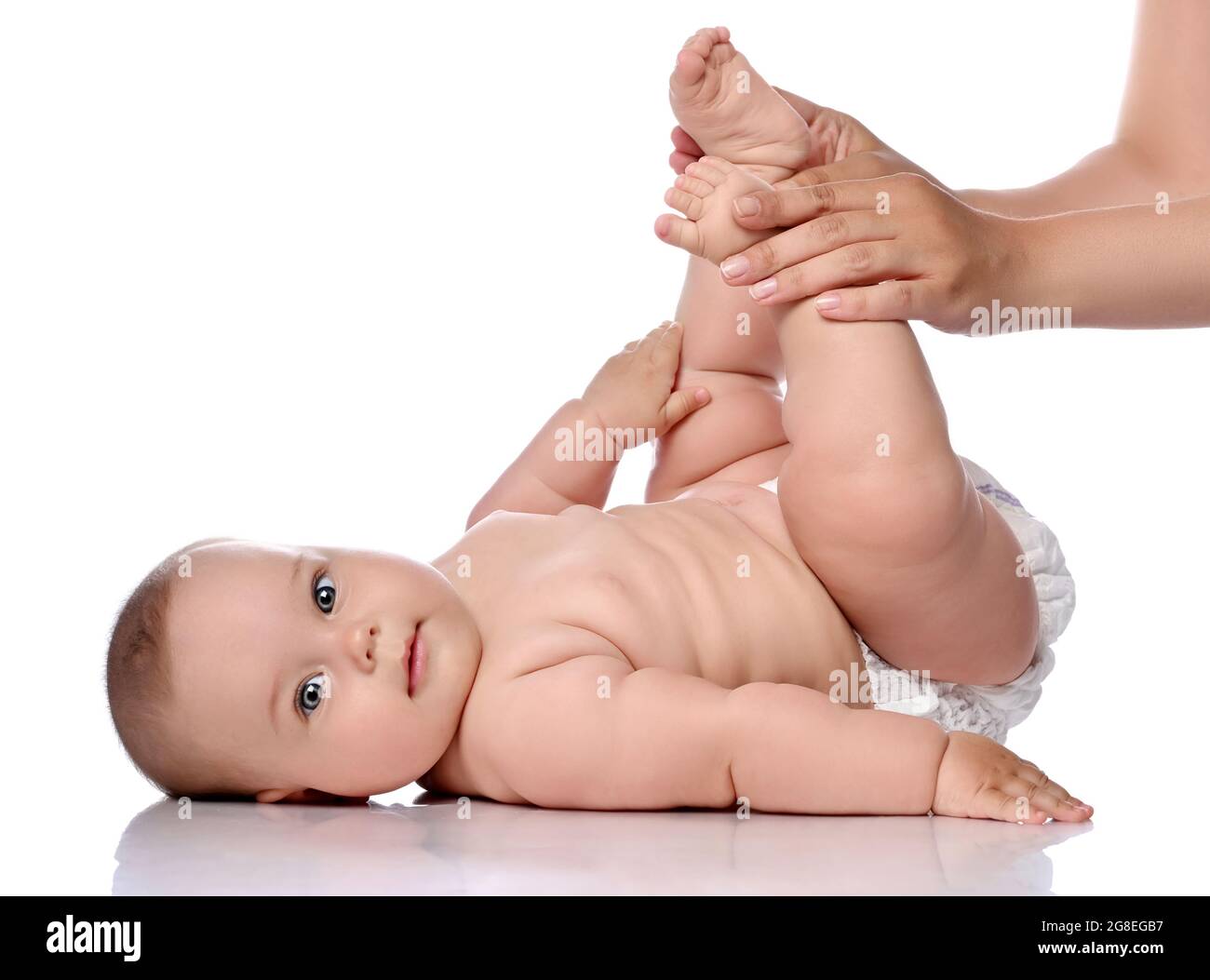 Kleinkind Baby Mädchen Kind in Windel liegt auf ihrem Rücken macht Übungen, Knie mit erwachsenen Trainer, Mutter beugen. Seitenansicht Stockfoto