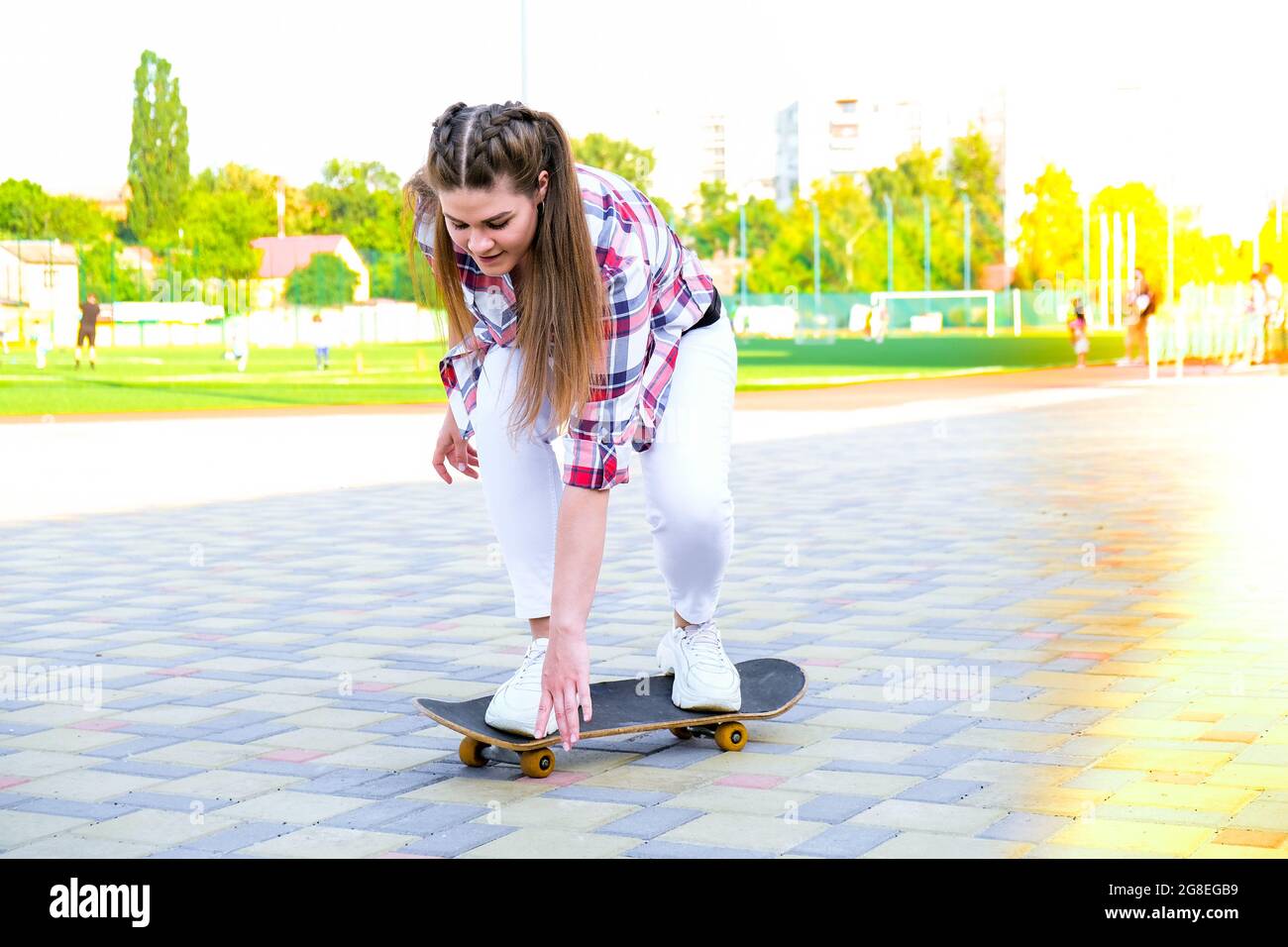 Junge Millennial Frau Hippie auf Skateboard sitzen. Summer Skate Sessions.  Sport Skateboarding. Frau, die auf einem Longboard in einem Park fährt.  Unbeschwerte Skaterin 20er Jahre genießen Freiheit Jugend Lebensstil.  Zurück zu normalen
