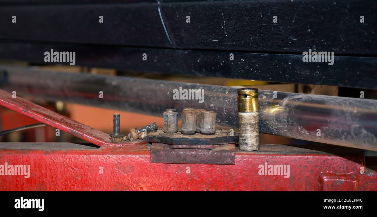 Metallköpfe eines pneumatischen Steckschlüssels an der Hubstütze. In der Garage wechselt ein Mann Teile an einem Fahrzeug. Konzept für kleine Unternehmen, Reparatur- und Wartungsservice für Fahrzeuge. UHD 4K. Stockfoto