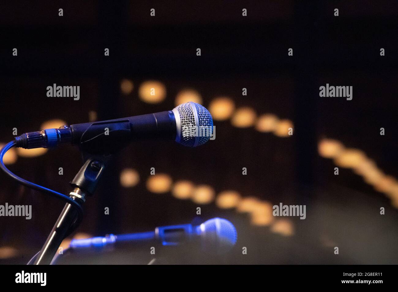 Konzertmikrofone mit unfokussieren Bokeh-Lichtkugeln, die Stand-up-Comedy-Live-Performance-Musik in einer Club-Bar-Kneipe zeigen, während sich die Welt öffnet Stockfoto