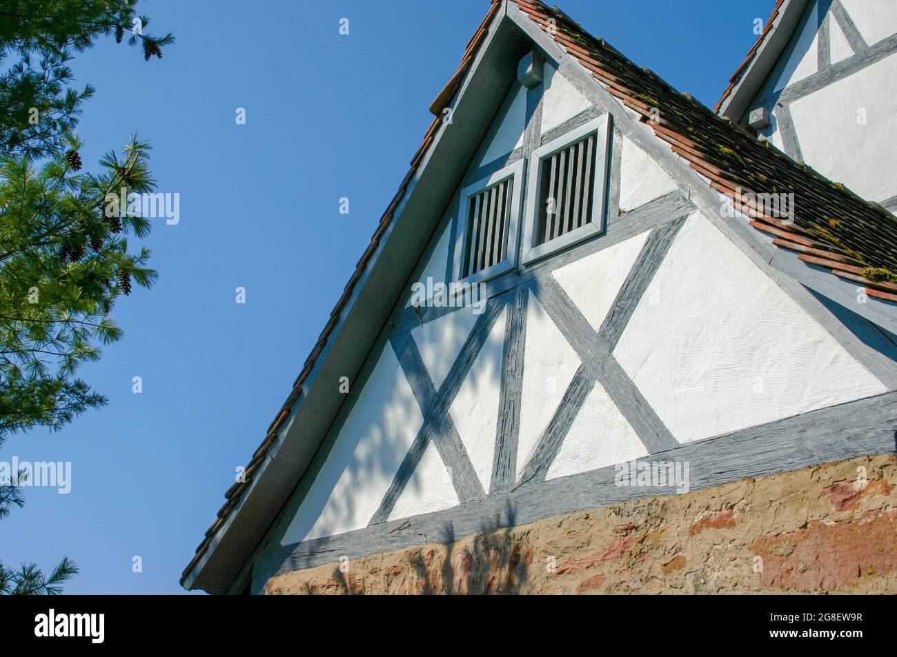 Giebel-Wand eines typischen Fachwerkhauses mit Backstein im ersten Stock in Deutschland vor blauem Himmel Stockfoto