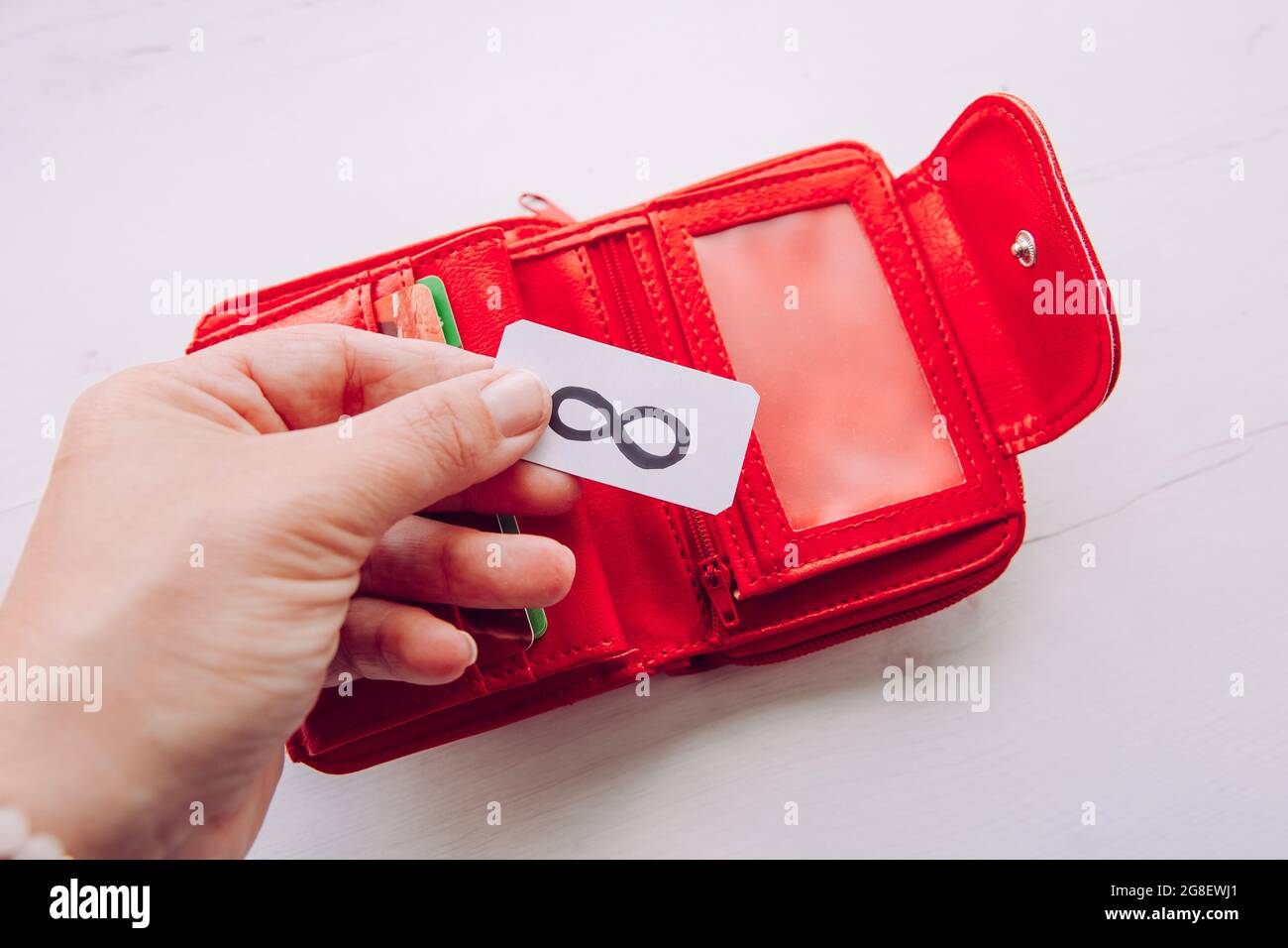Manifestieren des Geldkonzepts. Nahaufnahme der Frau Person Hand hält rote Brieftasche und Symbol der Unendlichkeit, um mehr Reichtum und Geld anzuziehen. Stockfoto
