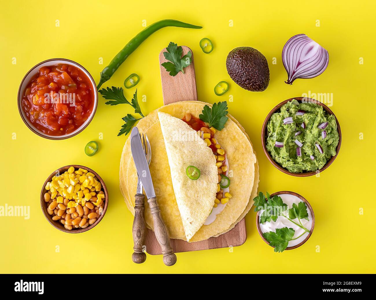 Tortilla Wrap oder Burrito mit Mais, Bohnen, Gemüse und hausgemachten Guacamole. Vegetarische gesunde Lebensmittel, gelber Hintergrund. Stockfoto