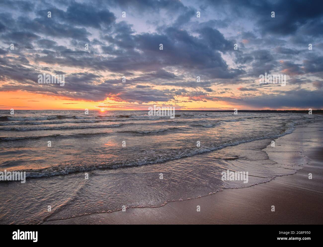 Ostsee-Panorama bei Sonnenuntergang mit Uferwellen und Sonne am Horizont. Stockfoto