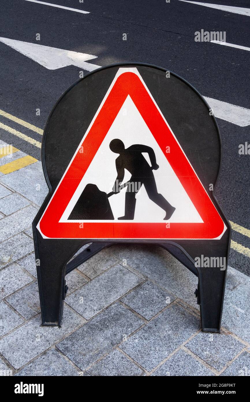 Männer arbeiten Warnschild auf einer Straße in England Stockfoto