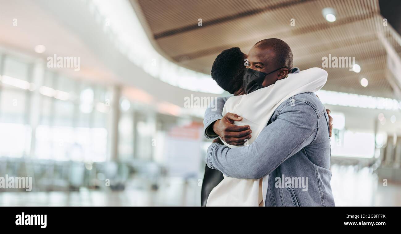 Afrikanisches Paar, das sich umarmt, nachdem es voneinander getrennt wurde. Männlicher Reisender, der seine Frau am Flughafen umarmt. Stockfoto