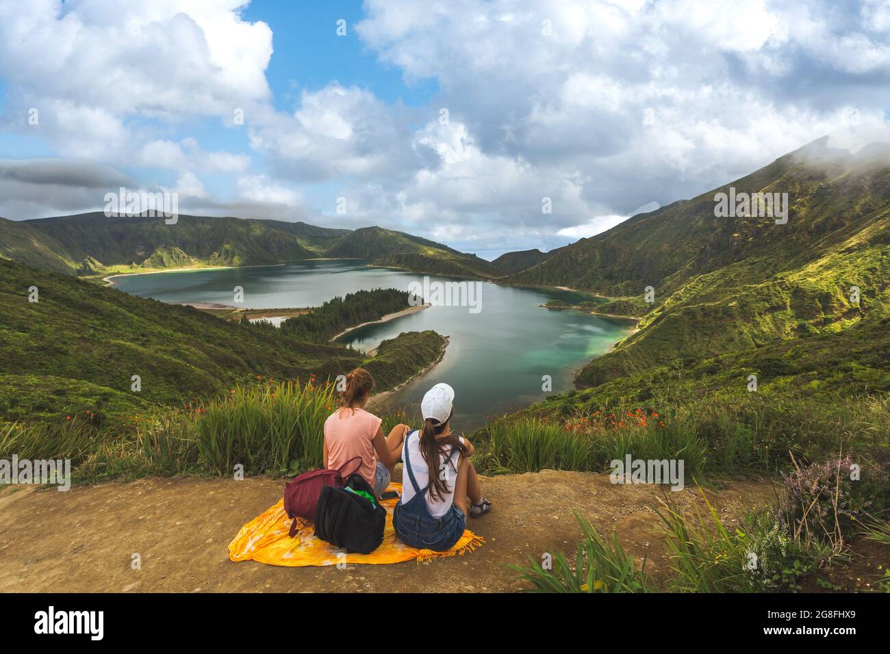 Rückansicht von zwei Freunden auf der Hügelkuppe gegen schöne Sommerlandschaft mit Wald und See im Sommer. Touristen bewundern wunderbare Natur auf den Azoren Stockfoto