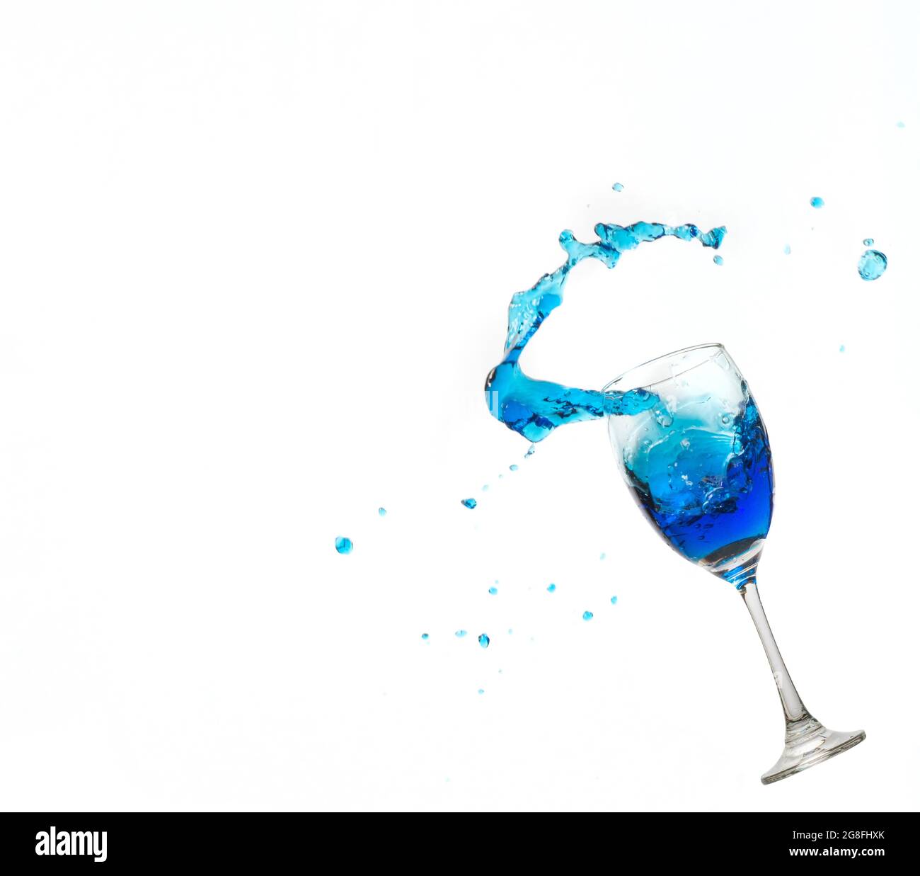 Weinglas auf weißem Hintergrund mit einem blauen Wasserspritzer. Stockfoto