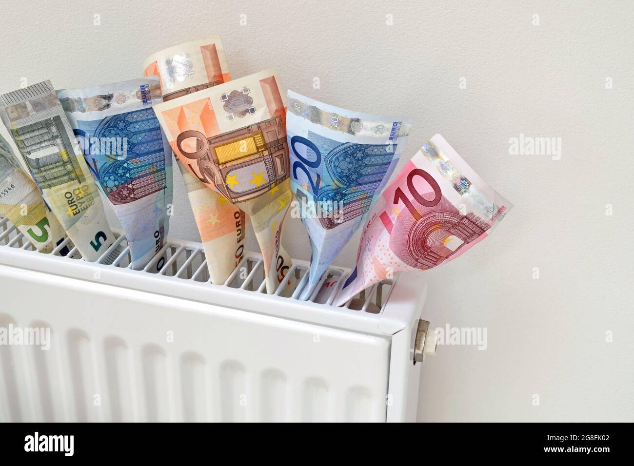 Euro-Banknoten, die aus einem Heizkörper kommen und Wärme als Geld symbolisieren. Stockfoto