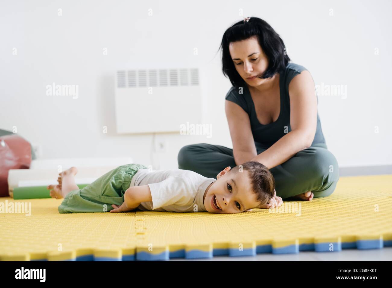 Rehabilitation von Kindern mit zerebraler Lähmung in einem speziellen Zentrum. Mutter macht körperliche Übungen und glücklich spielen mit Jungen, Sport-Aktivitäten für Stockfoto