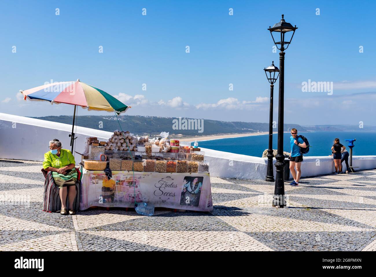 Nazare, Portugal - 28. Juni 2021: Frauen in traditioneller Kleidung verkaufen getrocknete Früchte auf dem Miradouro do Suberco Stockfoto