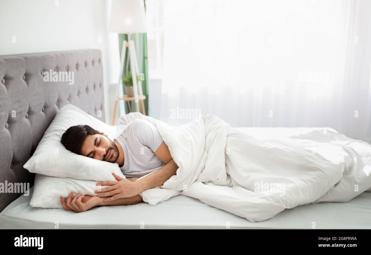 Schlafenszeit. Müde tausendjährigen arabischen Mann schläft, friedlich in  weißen komfortablen Bett im Schlafzimmer ruhen, Kopierer Platz  Stockfotografie - Alamy