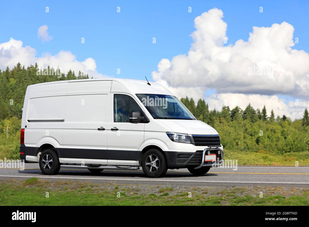 Weißer Lieferwagen transportiert Güter an einem schönen Sommertag entlang der Straße. Stockfoto