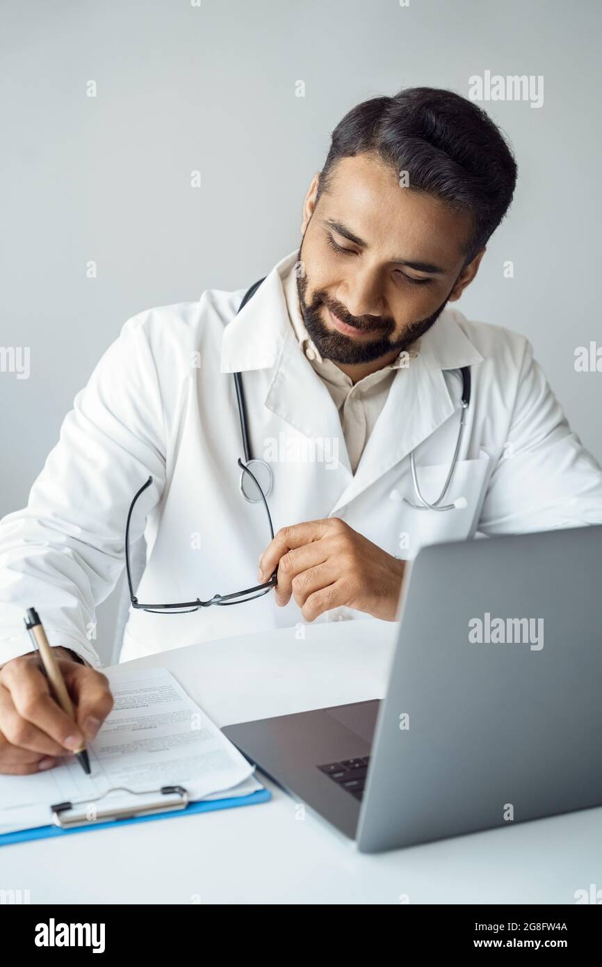 Vertikales Porträt des Arztes beim Schreiben auf die Patientenkarte während der Online-Konsultation Stockfoto