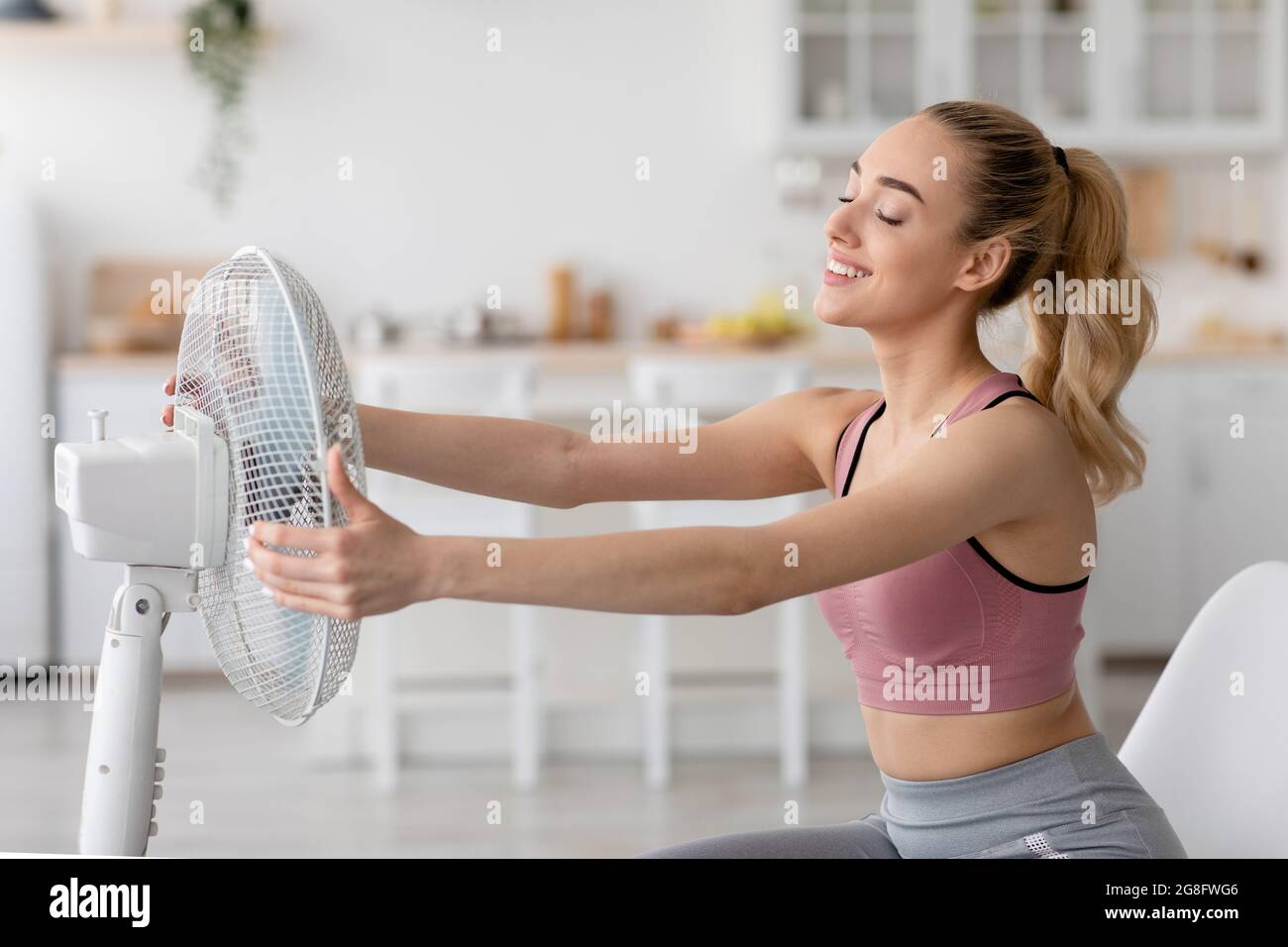 Die tausendjährige kaukasische Dame im Wohnzimmer atmet frische Luft aus der Bodenbelüftung, die auf sich selbst lenkt Stockfoto