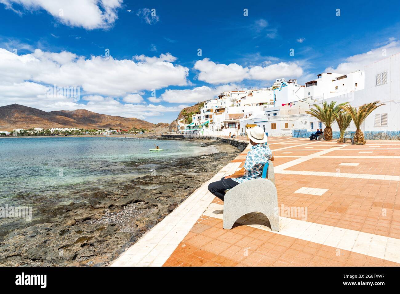 Touristen mit Strohhut bewundern das Meer auf einer Bank in Las Playitas sitzen, Fuerteventura, Kanarische Inseln, Spanien, Atlantik, Europa Stockfoto