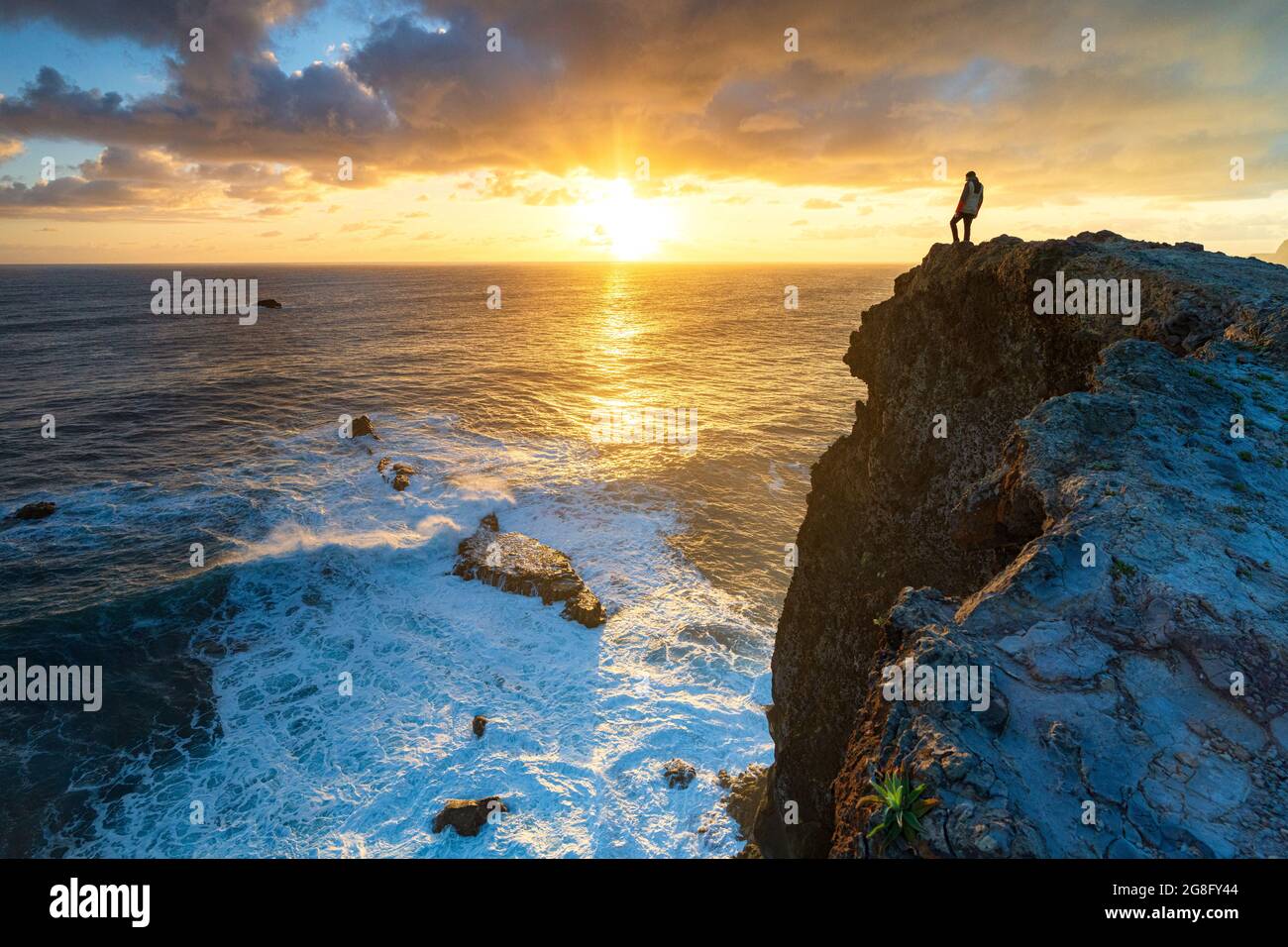 Ein Mann, der den Sonnenaufgang über den Meereswellen von den Klippen, der Insel Madeira, Portugal, dem Atlantik und Europa aus beobachtet Stockfoto
