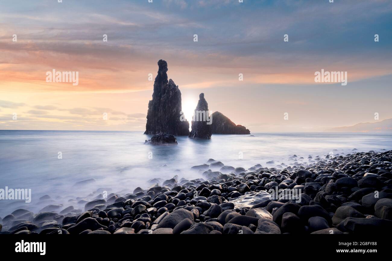 Wellen schlagen am vulkanischen Steinstrand und den Meeresstapeln von Ilheus da Rib und Ribeira da Janela bei Sonnenaufgang, auf der Insel Madeira, Portugal, im Atlantik, in Europa Stockfoto