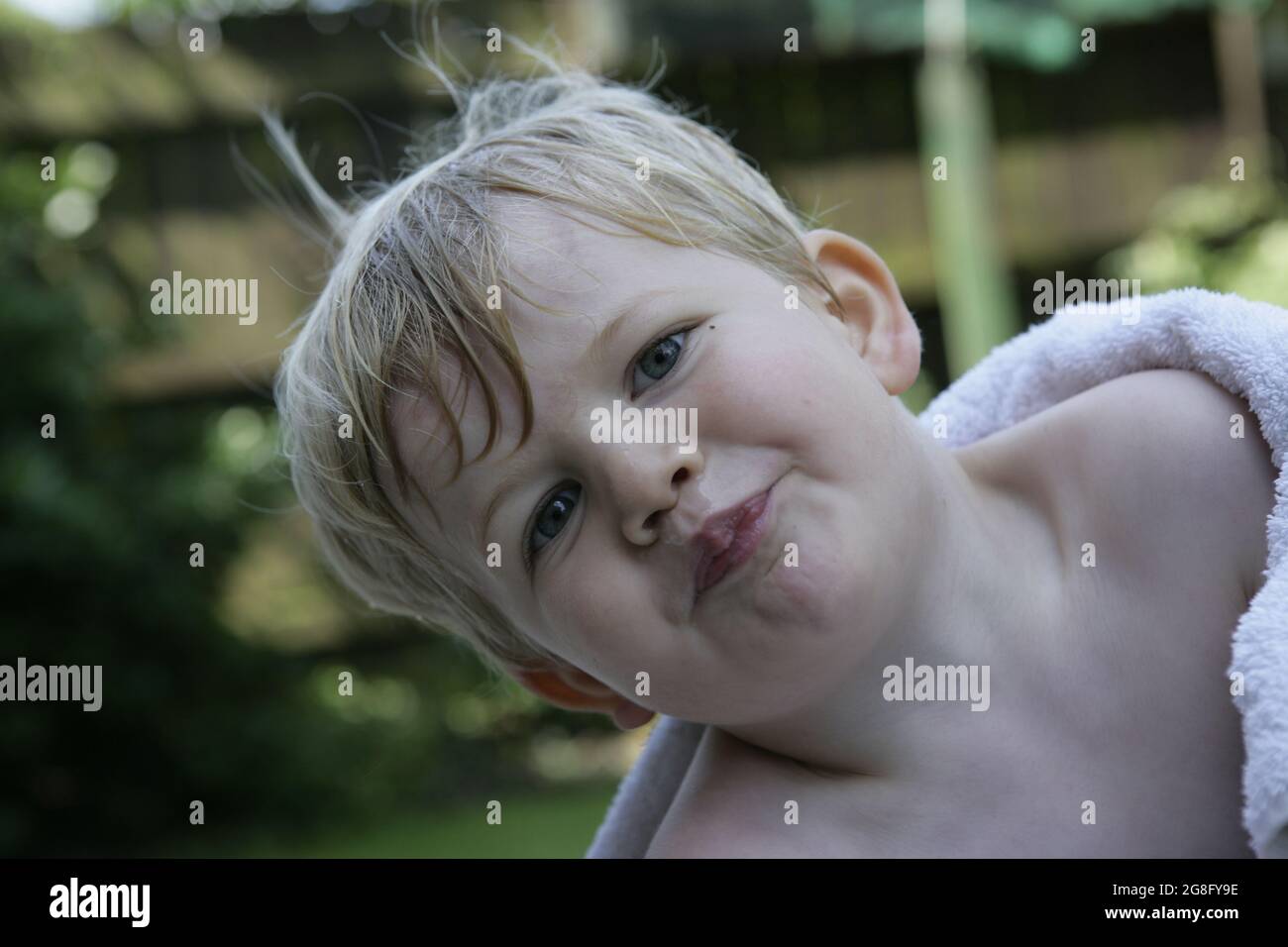 Outdoor Sommer Garten Porträt von jungen Kleinkind Kind mit blonden Haaren in Handtuch gewickelt Stockfoto