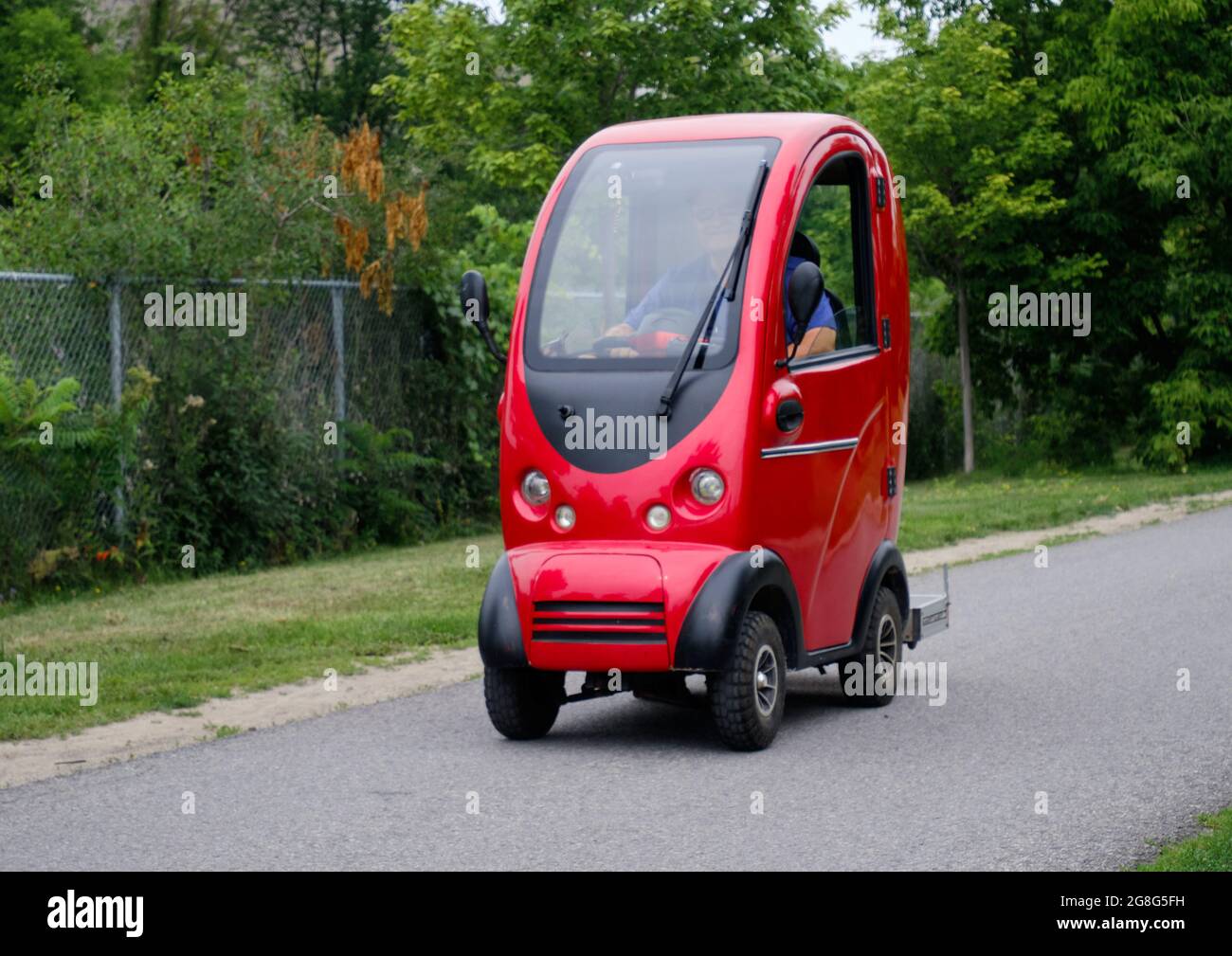 Älterer Mann, der auf einem Weg in Ottawa, Kanada, einen komplett geschlossenen Allwetter-Motorroller fährt Stockfoto