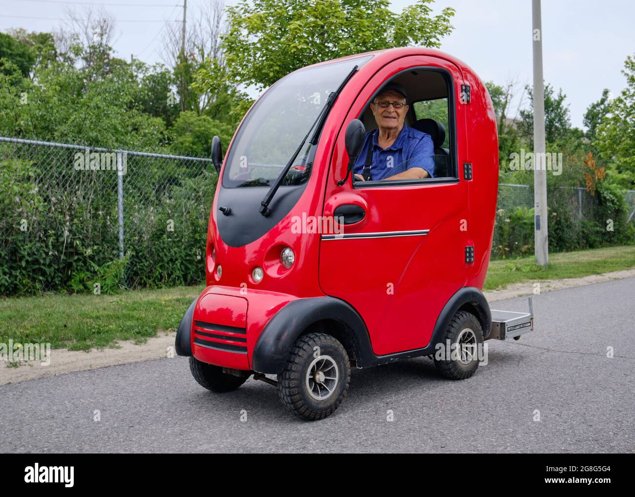 Älterer Mann, der auf einem Weg in Ottawa, Kanada, einen komplett geschlossenen Allwetter-Motorroller fährt Stockfoto