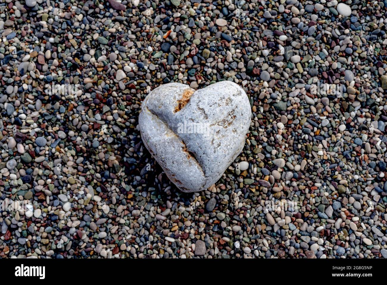 Ein herzförmiger Stein liegt an einem Kiesstrand. Liebeskonzept. Stillleben. Stockfoto