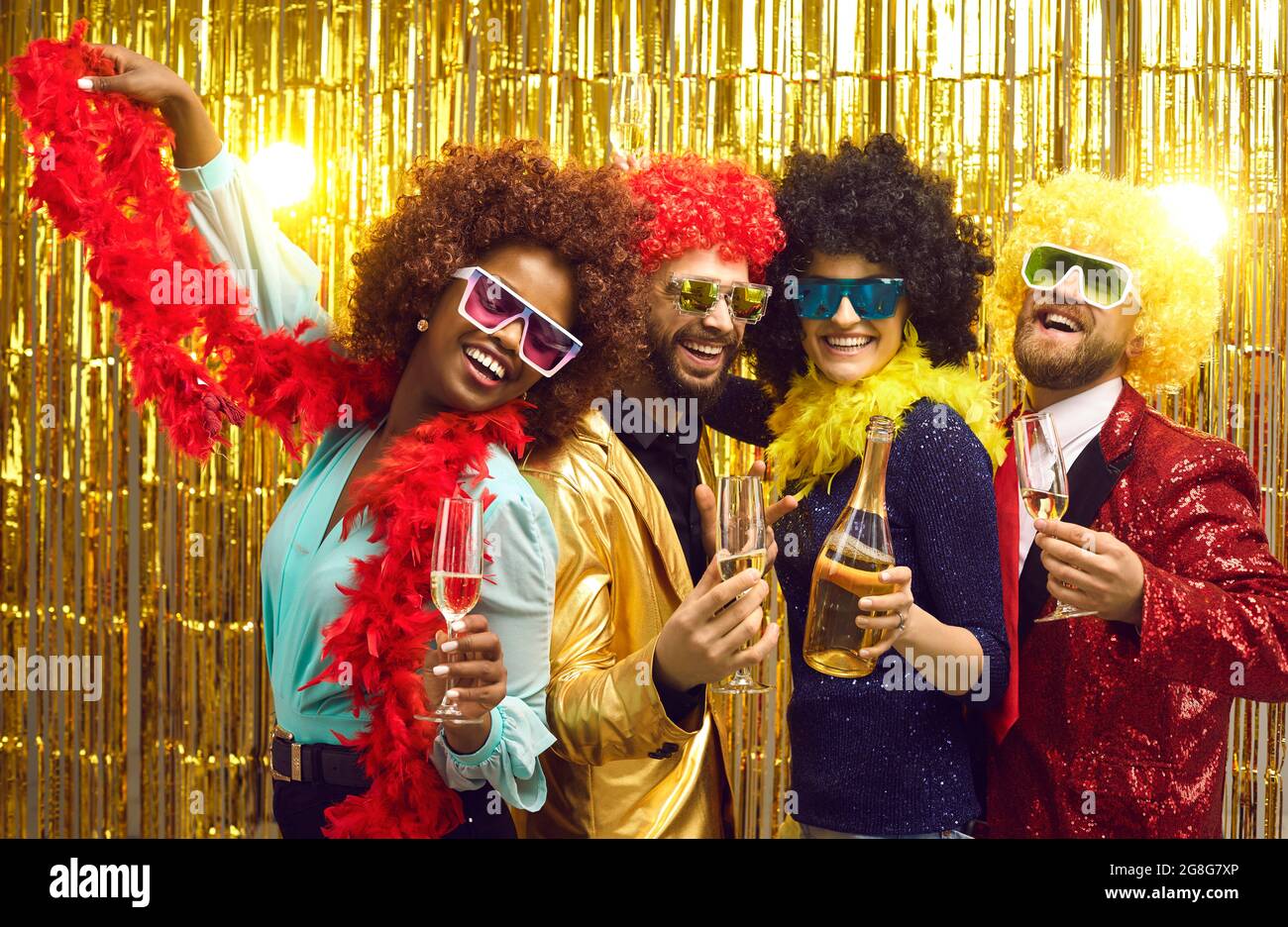 Eine Gruppe von vier Freunden lacht und teilt gute und positive Stimmung mit Champagner Stockfoto