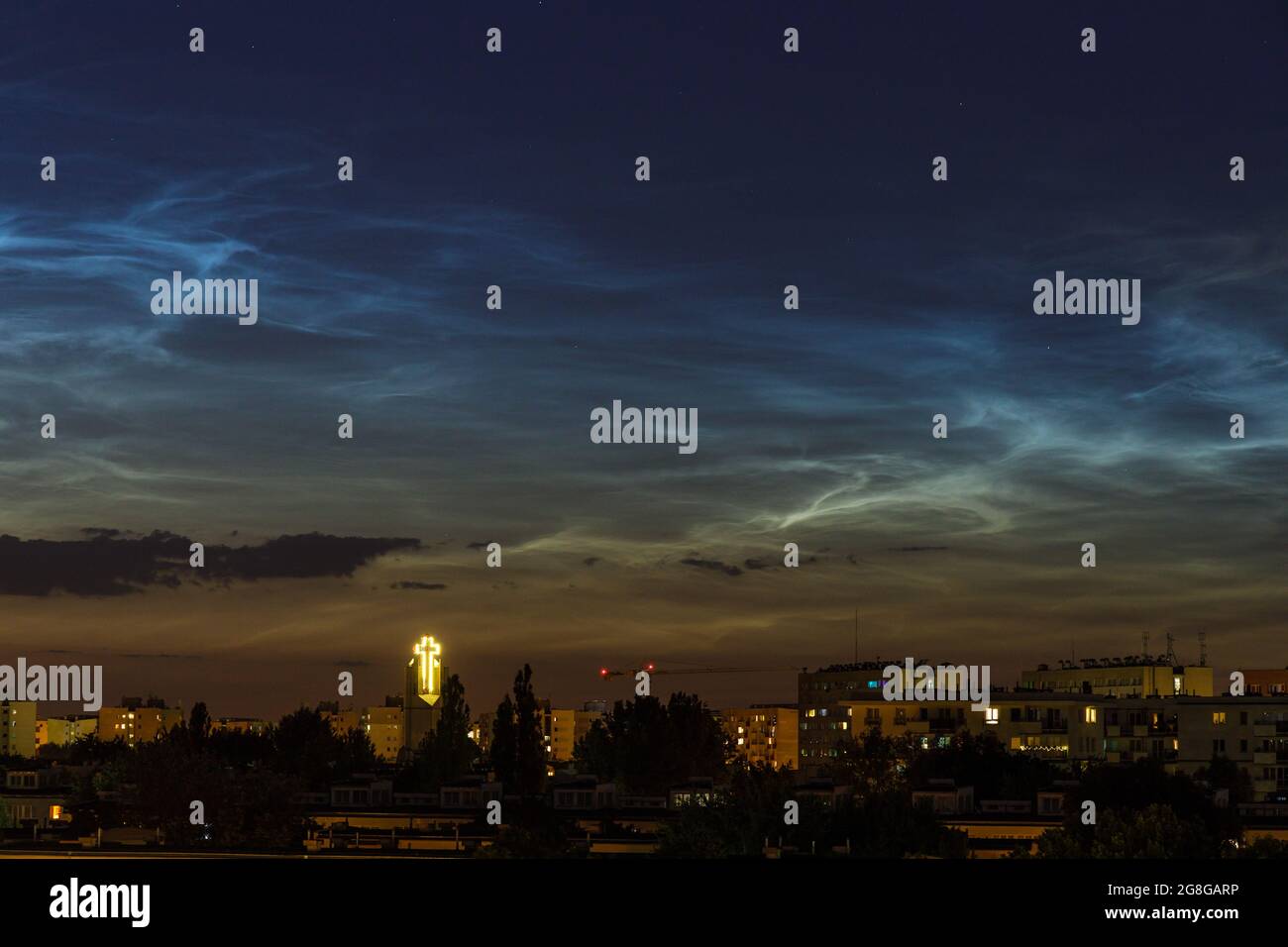 Nächtliche Wolke (NLC, Nachtwolken) über Wohnprojekt und Kirche am Abend. Wolkenähnliche Phänomene in der Mesosphäre. Es sind die höchsten Wolken in E Stockfoto