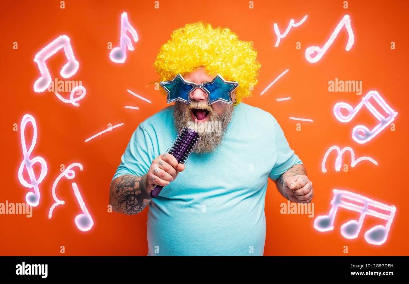 Ein fetter Mann mit Bart, Tattoos und Sonnenbrillen singt ein Lied Stockfoto