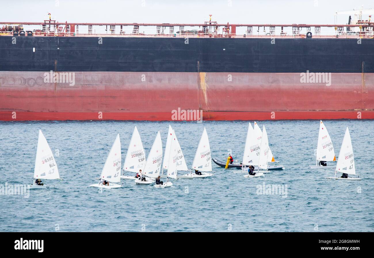 Kleines Segelschiff in der Nähe von großen Öltankern. Stockfoto