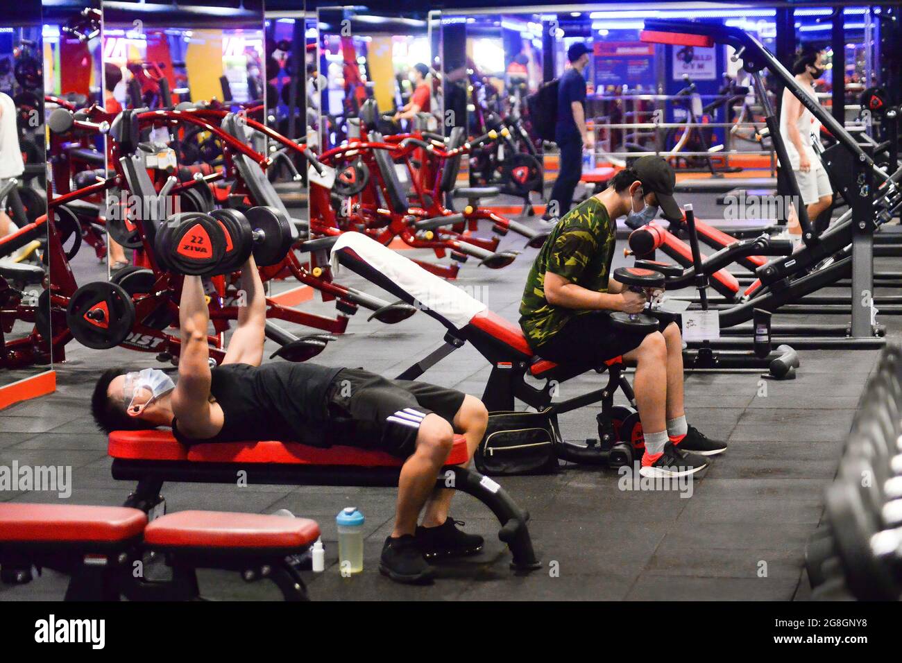 Menschen, die Gesichtsmasken tragen, heben Gewichte in einem Fitnessstudio in Taipeh. Das taiwanesische CDC kündigte neue Leitlinien zur Lockerung der Pandemiebeschränkungen an. Stockfoto