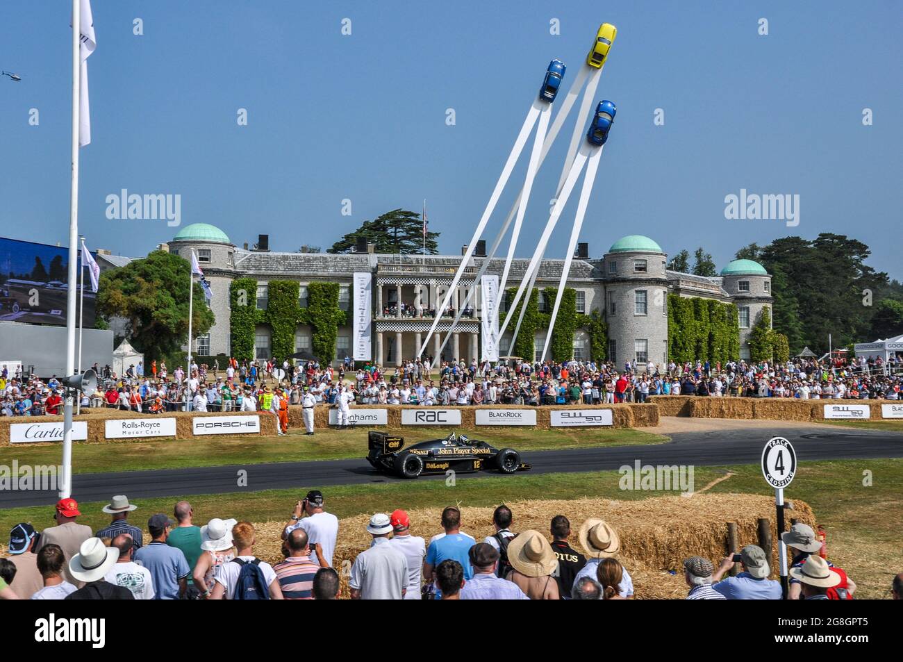 Sennas Lotus 98T-Rennwagen fährt beim Goodwood Festival of Speed in Großbritannien auf der Anhöhe, vorbei an Goodwood House und dem zentralen Porsche-Feature Stockfoto