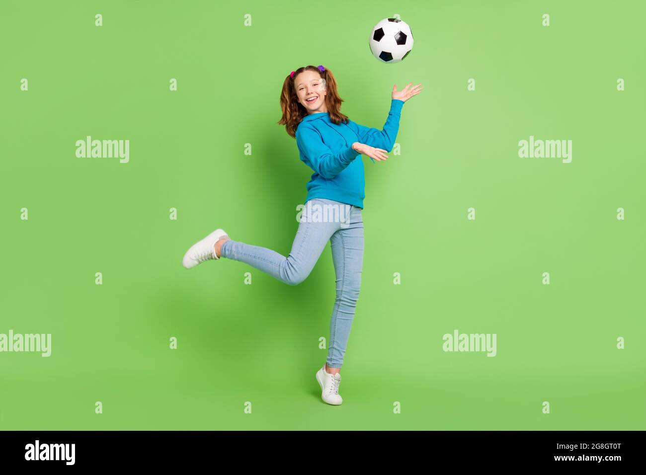 Foto in voller Größe von Brünette Pferdeschwanz behaart kleines Mädchen fliegen Fußball sportive isoliert auf glänzendes grünes Farbe Hintergrund Stockfoto