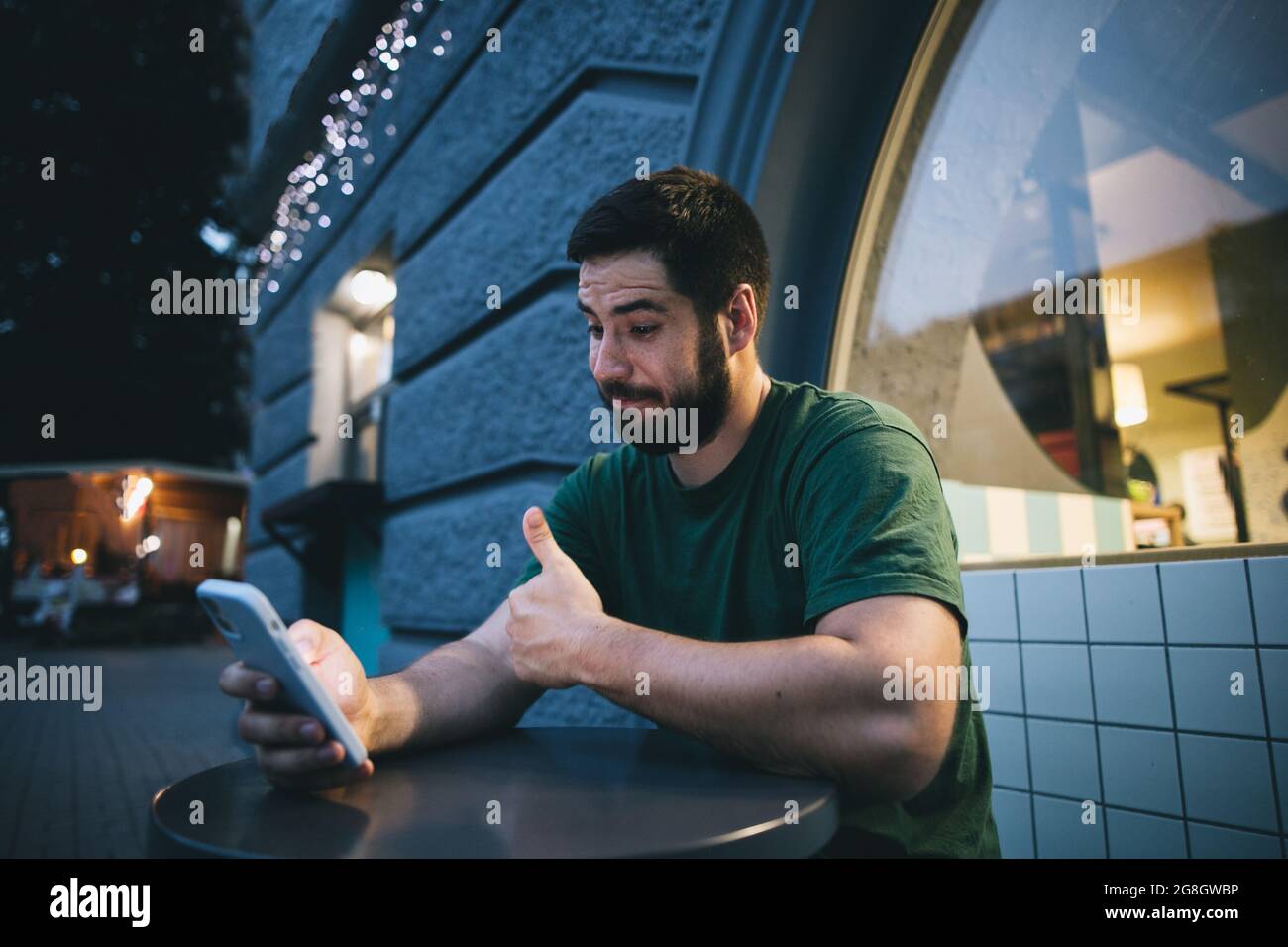 Ein junger Mann, der draußen den Videoanruf auf dem Mobiltelefon ansieht Stockfoto