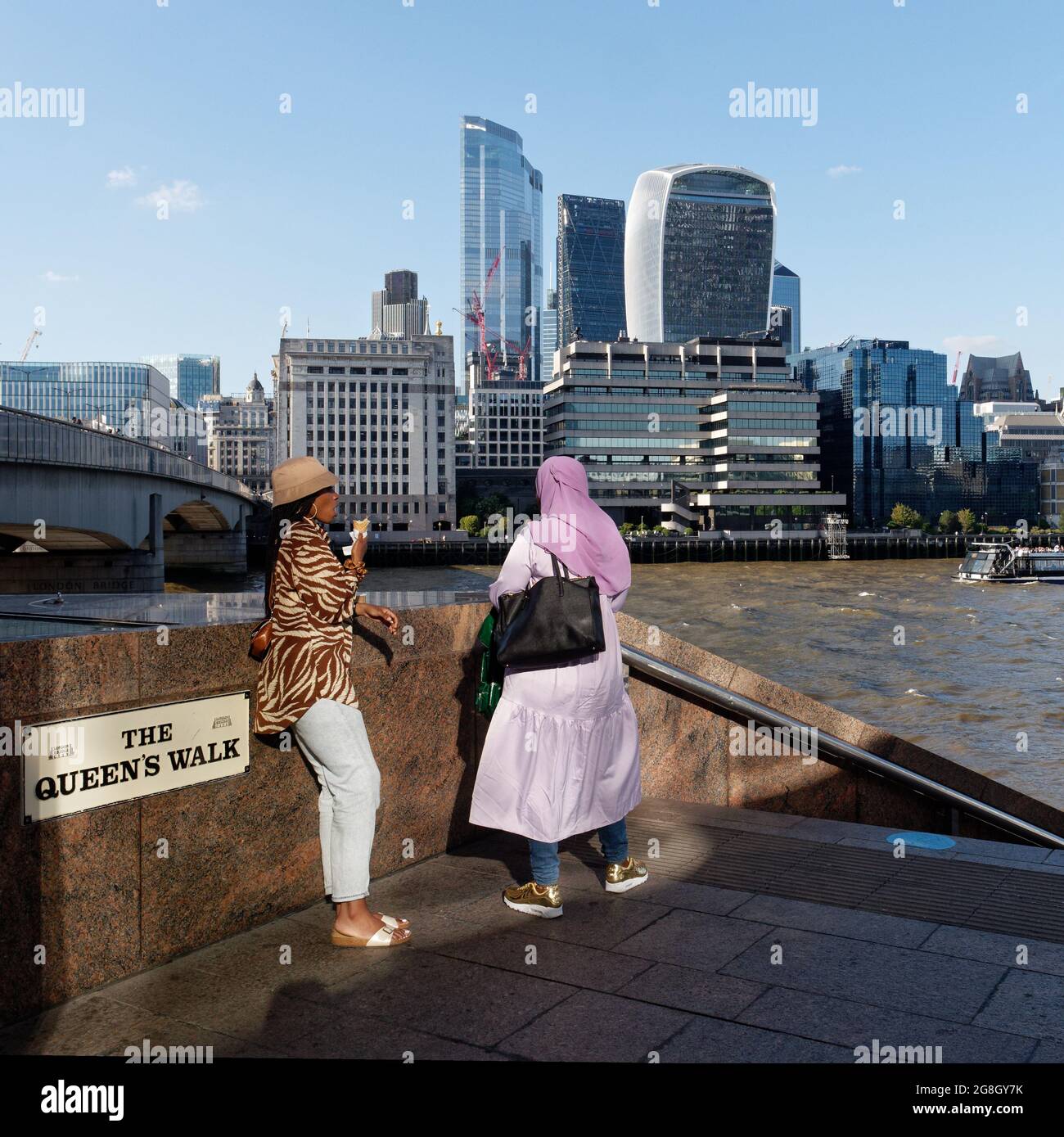 London, Greater London, England, Juni 12 2021: Themse mit dem Wolkenkratzer Walkie Talkie im Hintergrund, während zwei Damen sich im Vordergrund geselligen. Stockfoto