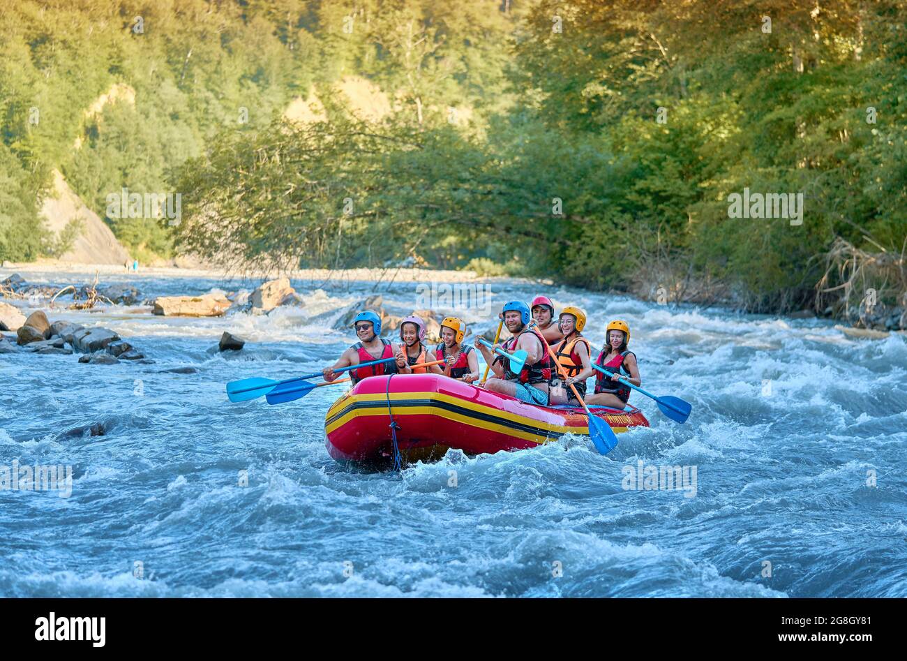 Gruppe von Touristen, die mit dem starken Strom des Gebirgsflusses kämpfen. Stockfoto