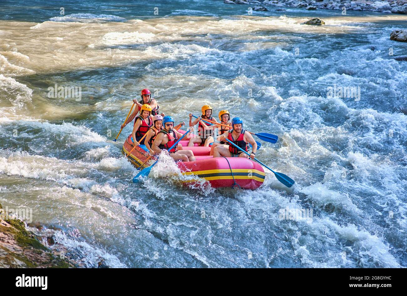 Gruppe von Touristen, die mit dem starken Strom des Gebirgsflusses kämpfen. Stockfoto