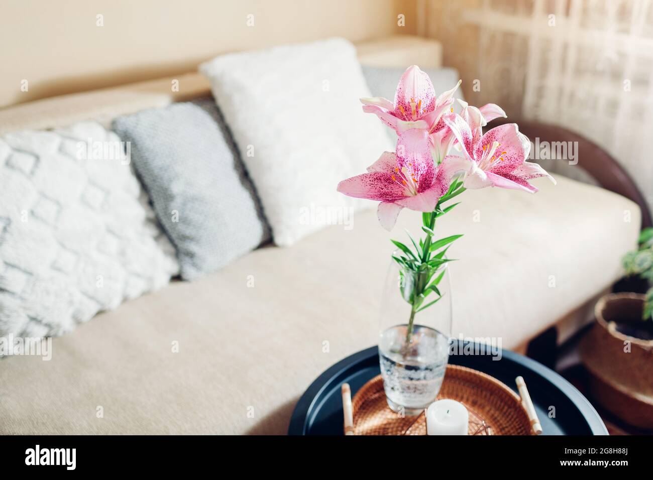 Inneneinrichtung und Inneneinrichtung. Frische rosa Lilienblumen in Vase im Wohnzimmer von der Couch. Blumenstrauß auf dem Couchtisch Stockfoto