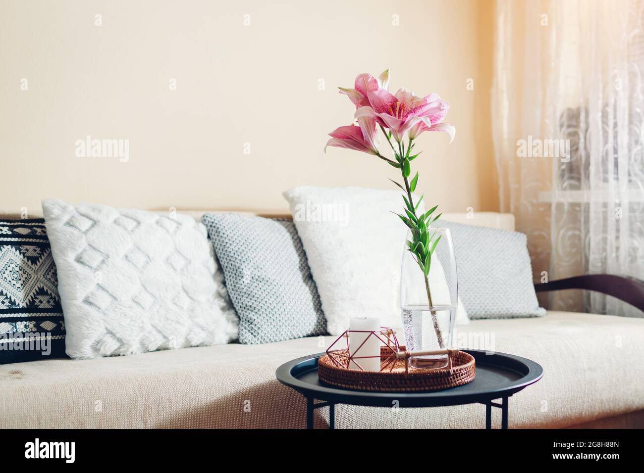 Inneneinrichtung und Inneneinrichtung. Frische rosa Lilienblumen in Vase im Wohnzimmer von der Couch. Blumenstrauß auf dem Couchtisch Stockfoto