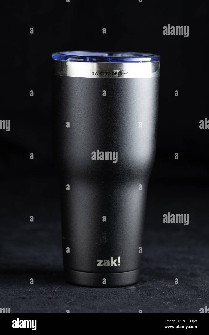 Großer isolierter Getränkebehälter mit Deckel, der verwendet wird, um Flüssigkeiten über einen längeren Zeitraum auf dunklem Hintergrund heiß oder kalt zu halten Stockfoto