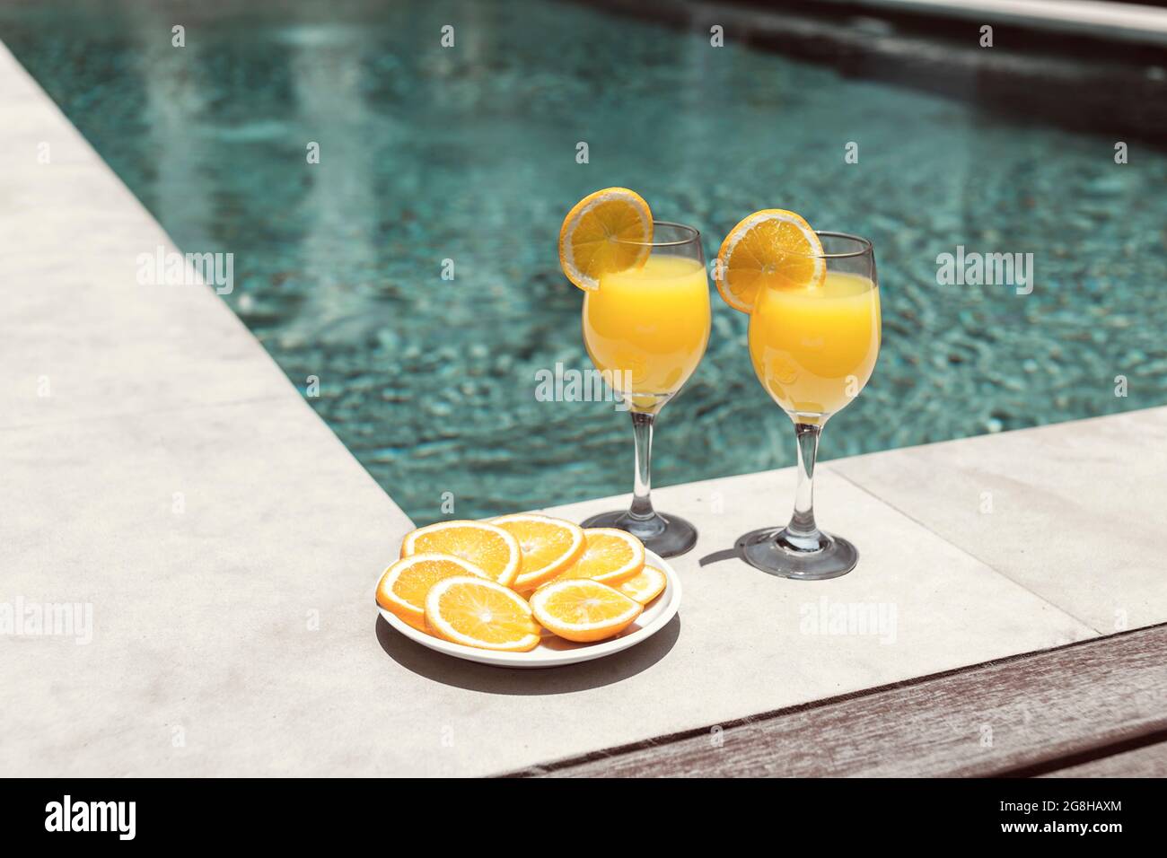 Glas mit Orangensaft in der Nähe des Pools Stockfoto